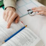 Close-up of a student studying math using a textbook and pencil at a desk indoors.