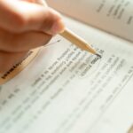 Close-up of a woman writing notes in a textbook, focusing on education and learning.